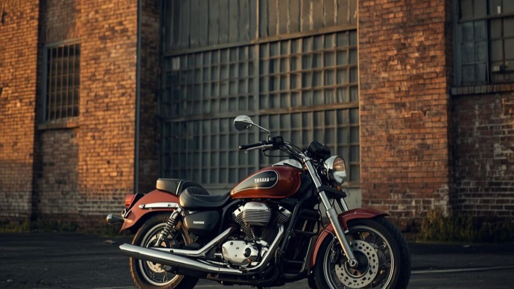 夕暮れ時の古い倉庫前に佇むバイク。ドラッグスター400をハーレー仕様のベースとしても人気を博した名車が、環境規制や時代の変化により生産終了に至った歴史的背景を感じさせる写真。