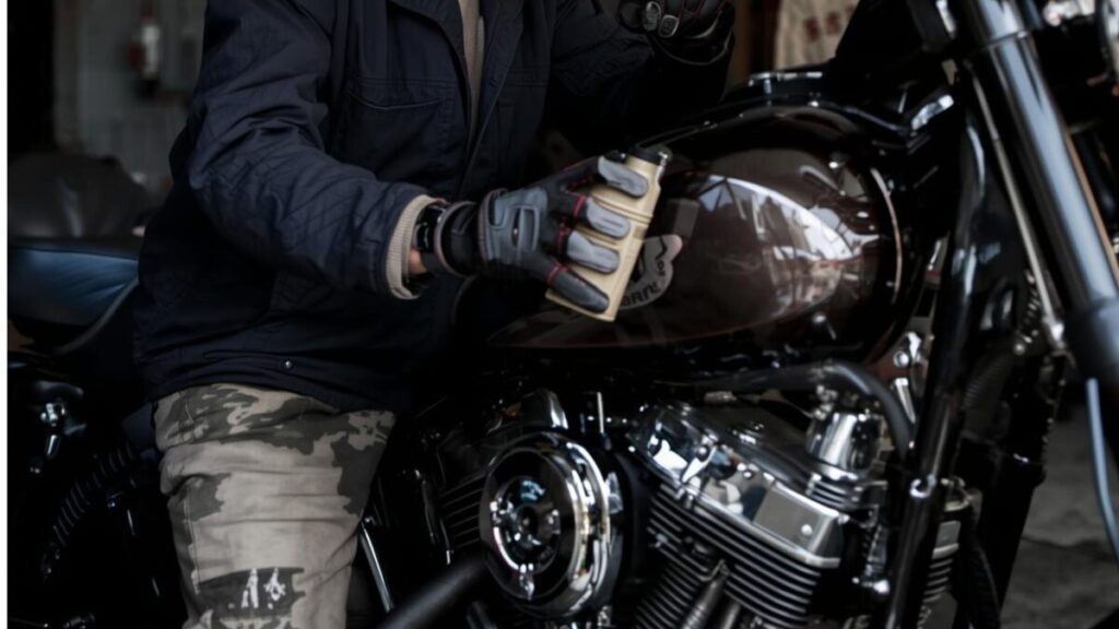 ガレージで愛車のメンテナンスを行う年配のライダー。ハーレーエボの人気車種を長く楽しむために必要な、日常的な手入れと維持管理への理解を促す日常の光景です。