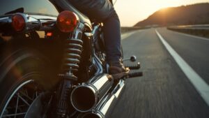 夕暮れの海岸線を走る50代の日本人男性と、精巧なハーレーの車検対応マフラー。法規制を遵守し、自分らしいスタイルでツーリングを楽しむ様子を描写しています。