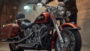 ガレージで愛車を点検するシニアライダーの姿。ハーレーのバッテリー寿命を延ばすための日常的なメンテナンスと、ツーリング前の準備の様子を自然な描写で表現しています。