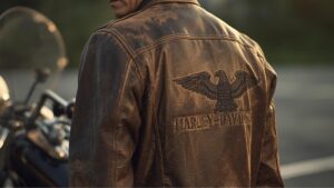 夕暮れ時のガレージで、愛車と共に佇む60代男性。使い込まれた質感が魅力的なハーレーダビッドソンの古着のレザージャケットを粋に着こなすシネマティックな光景。