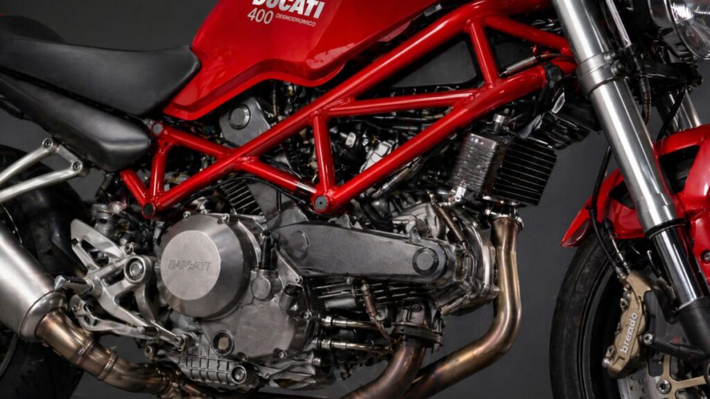 ドゥカティ モンスター400の象徴的なL型2気筒エンジンと赤いトレリスフレームのクローズアップ。精密な造形美を強調。