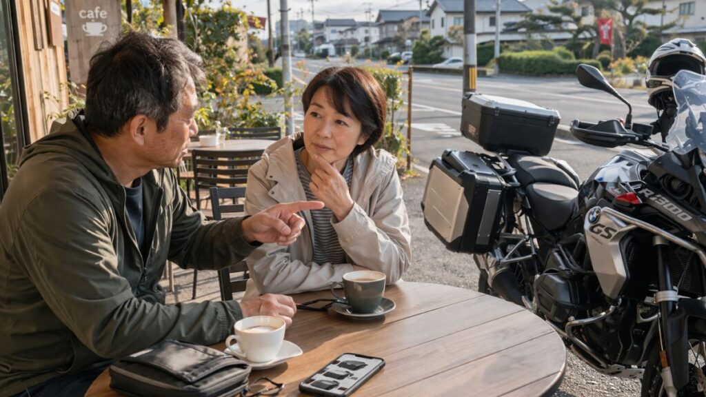 ツーリング途中のカフェで、R1300GS パニアケース 純正に合わせてトップケースが必要か相談する夫婦。