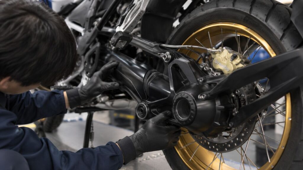 BMW R1250GSの後輪ファイナルドライブとシャフトドライブを点検するメカニックの手元接写。