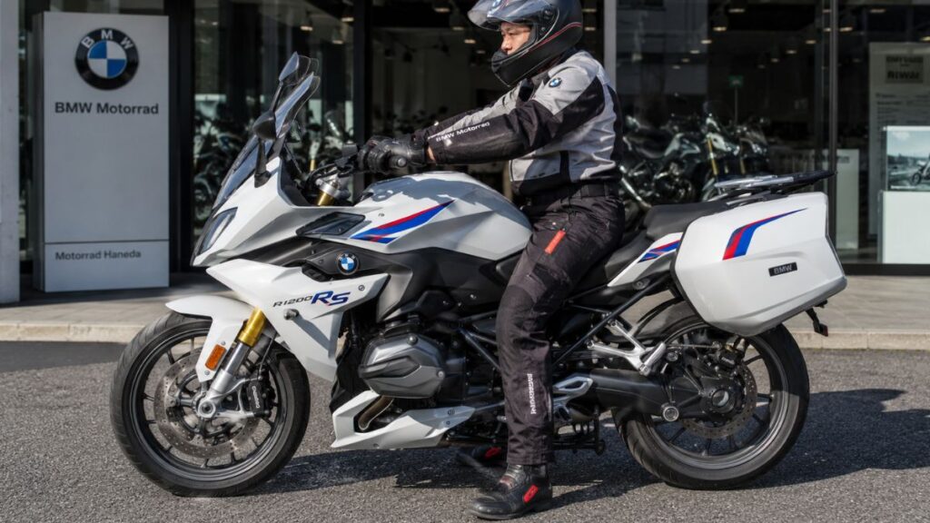 販売店前でBMW R1200RSにまたがり、足つきを確認するヘルメットを着用した日本人ライダー